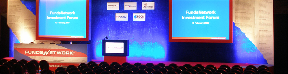 Conference hall with stage, blue lighting and two large projector screens