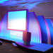 Custom−built stage with a series of backdrops, large projector screen and two podiums