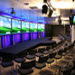 Presentation room with a large stage and row of five TV screens