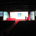 Conference theatre with five projector screens and individual presenting on stage